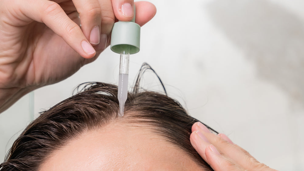 A lady applying Divi's scalp serum to her scalp