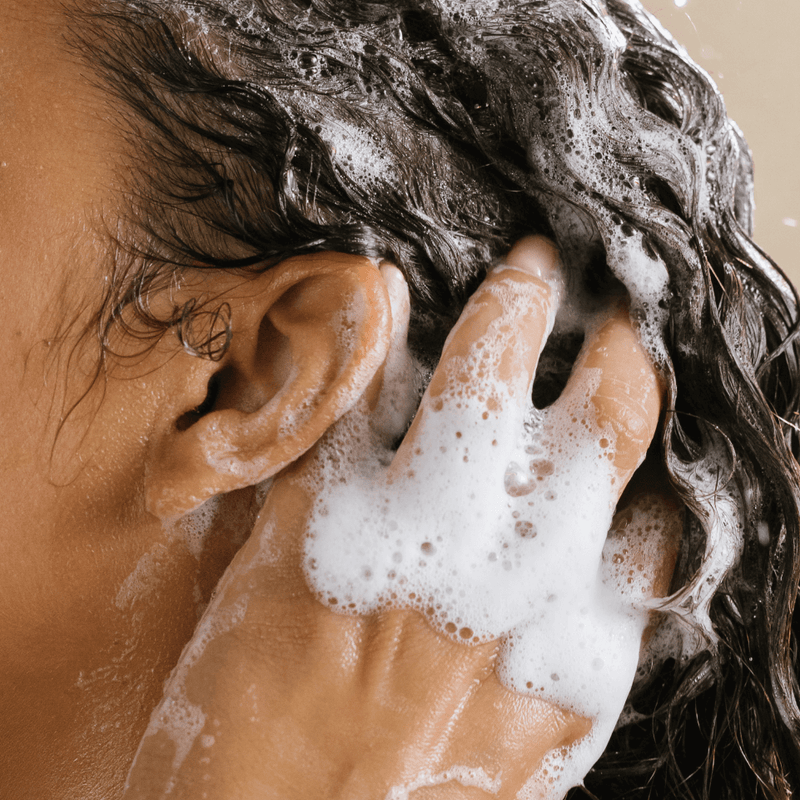 A woman cleaning her scalp and hair in the shower