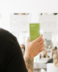 hair stylist holding divi product behind customers